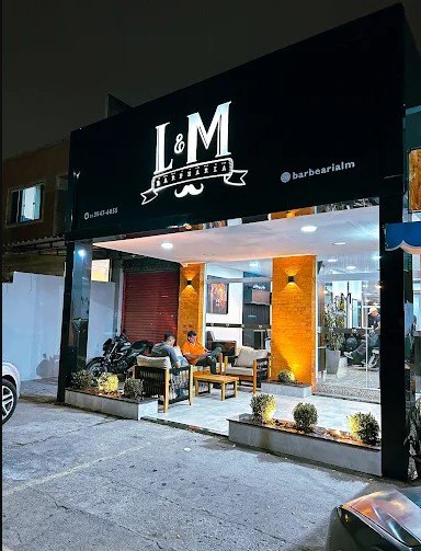 Fachada da L&M Barbearia à noite, com a identidade da marca e área de espera externa